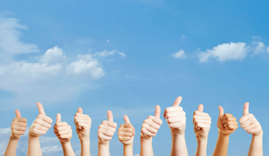Many hands over the sky with thumbs up as motivation
